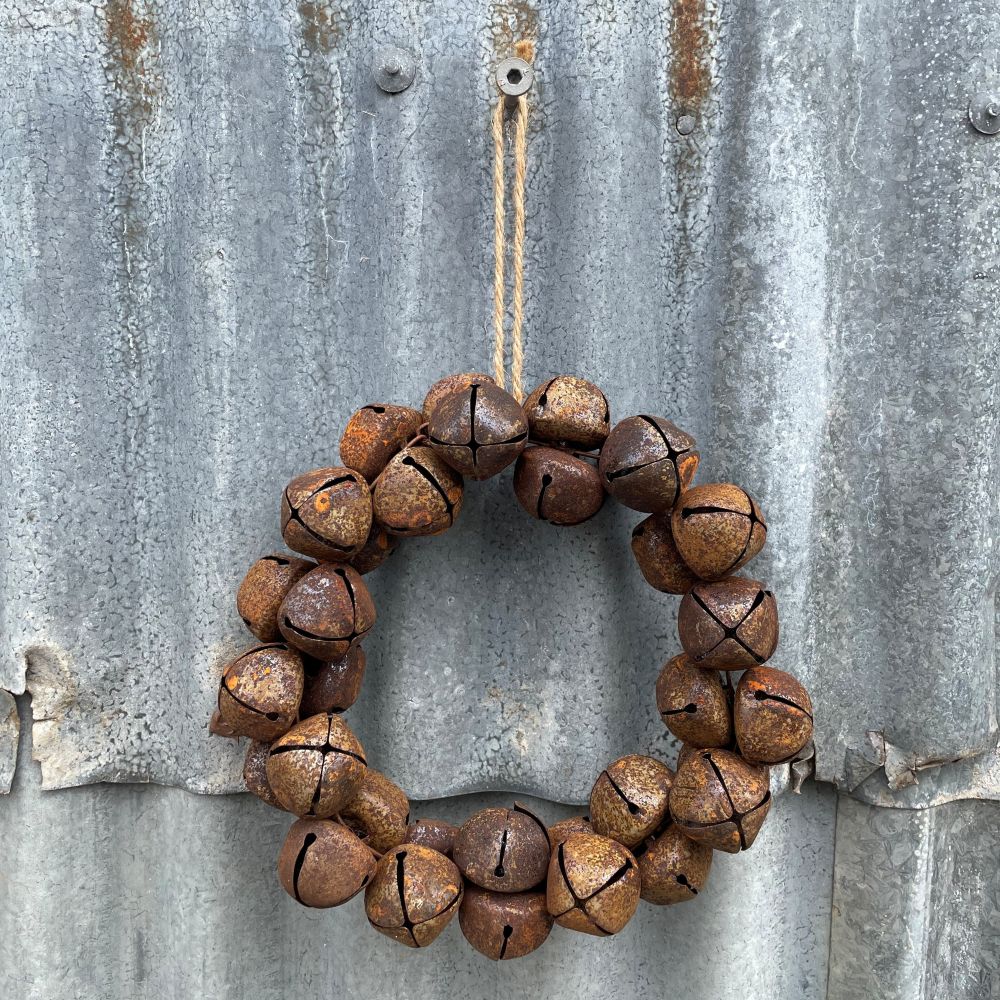 Wreath made of rusted metal bells hanging on a corrugated metal surface