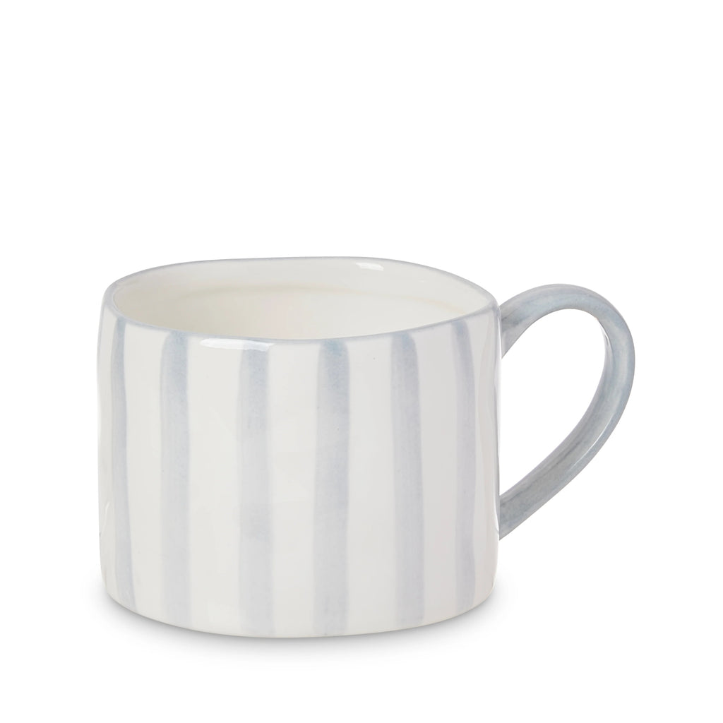 White ceramic mug with blue handle and blue hand painted stripes on a white background