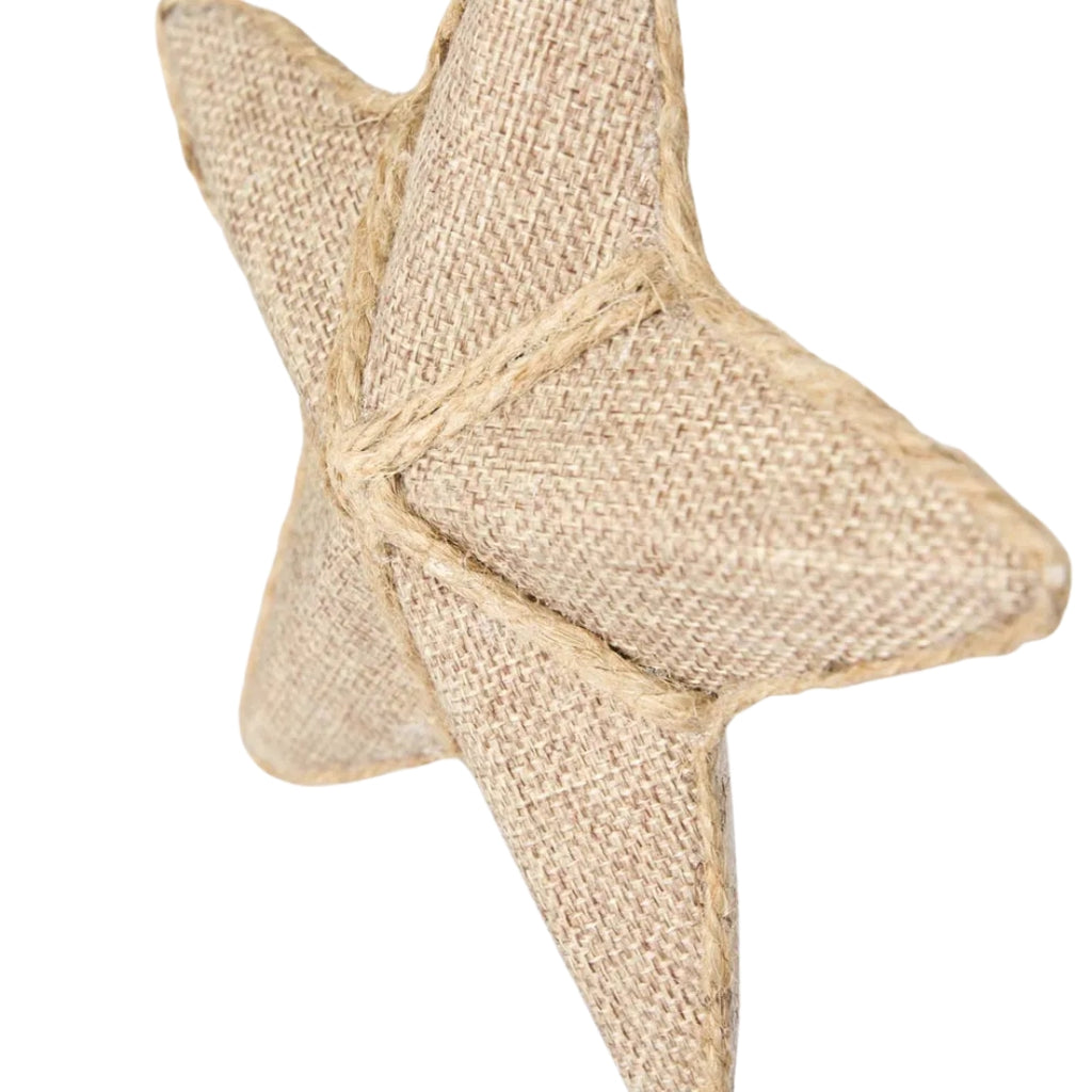 Star ornament made of linen-look fabric and jute detailing hanging on white background - side view