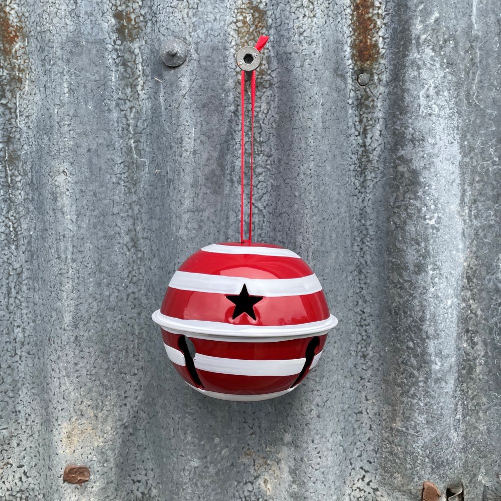 Red and white striped ball with a star cut out hanging on a textured metal surface