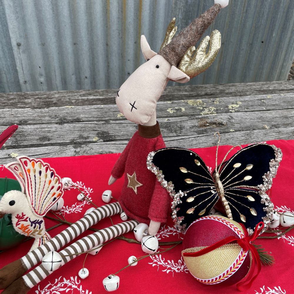 Carnival Christmas centrepiece with red table runner and display of moose, butterfly, bauble and humming bird decorations.
