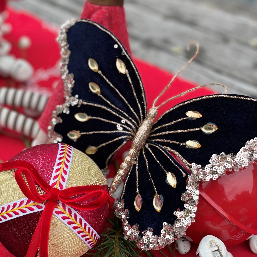 Decorative dark green butterfly ornament with sequins and beads on a blurred background