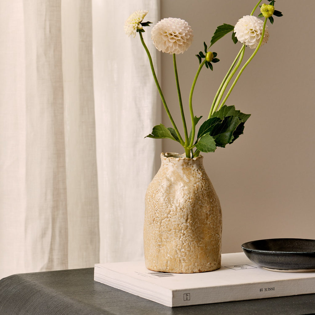Twig and Feather: Textured beige natural vase with flowers on a table against a neutral background - by Madras Link