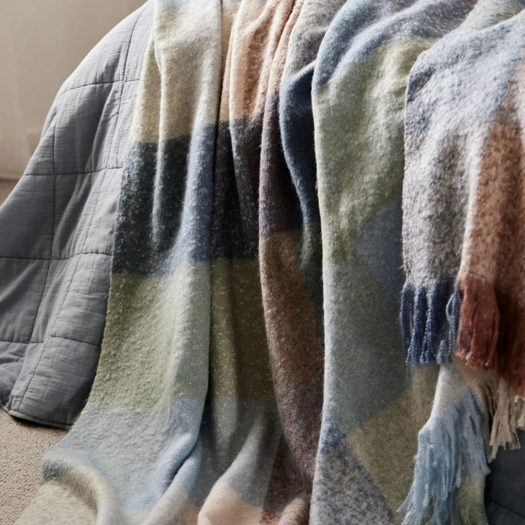 Twig and Feather Dana brushed throw rug in blue, brown and taupe check by Madras Link - shown on bed