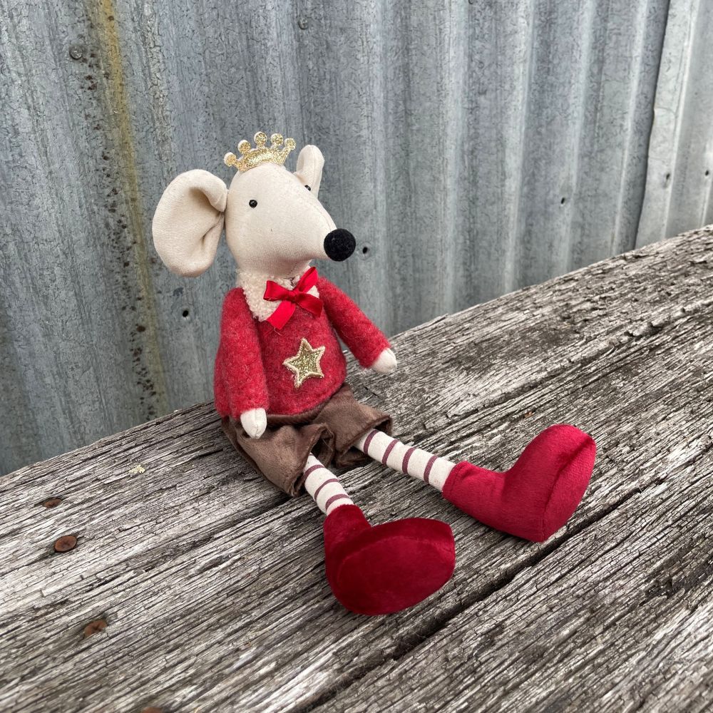 Fabric mouse decoration in a red outfit with a star and a crown on sitting on a wooden surface - side angle