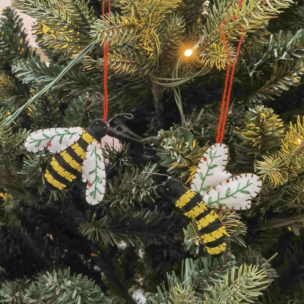 Decorative bee ornaments hanging on a Christmas tree.