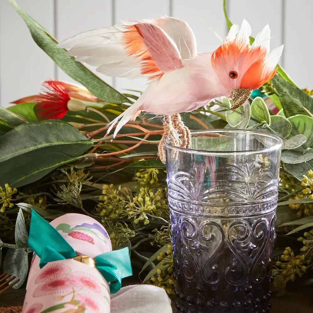 Decorative pink Major Mitchell cockatoo perched on a glass with floral and greenery background