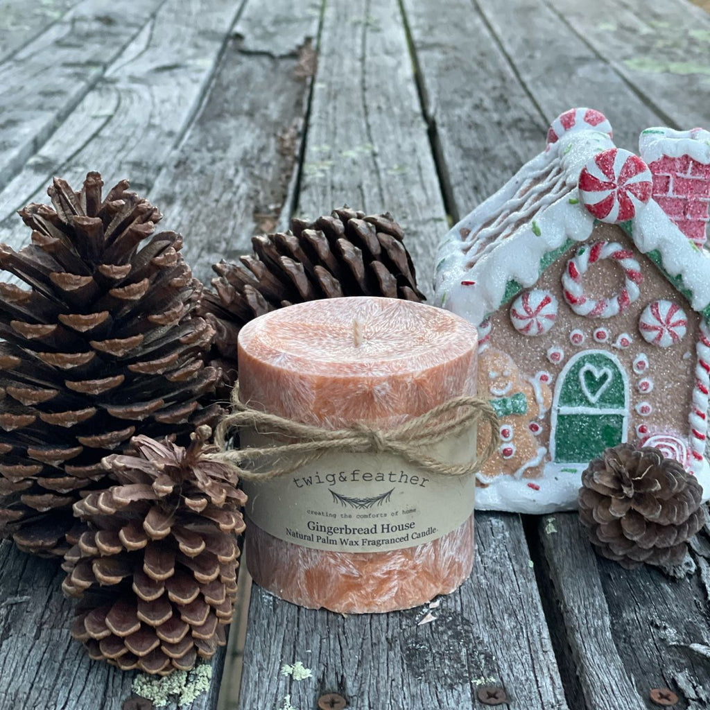Twig and Feather Gingerbread house palm wax pillar candle with pinecones on a wooden surface - 38 hours
