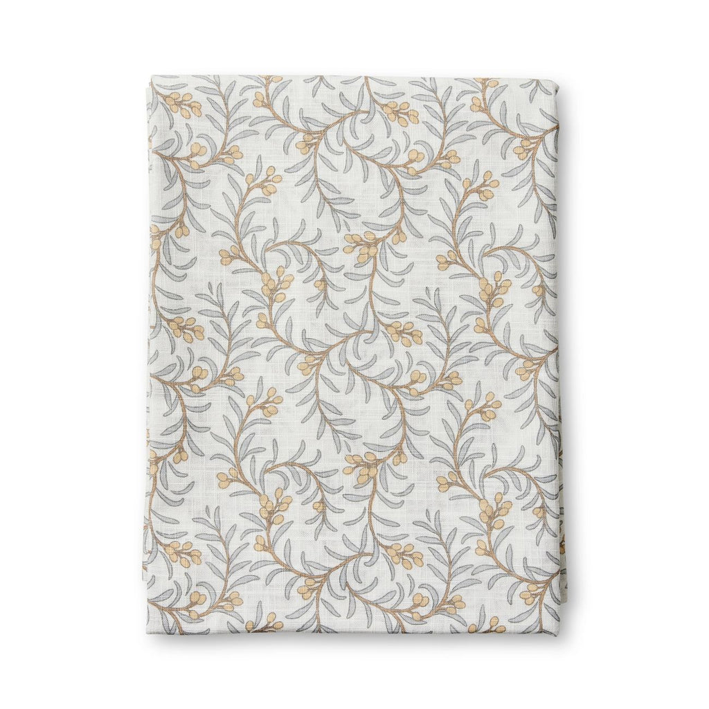 Juniper tablecloth featuring the floral patterned fabric with blue leaves and apricot coloured berries - folded on  a white background