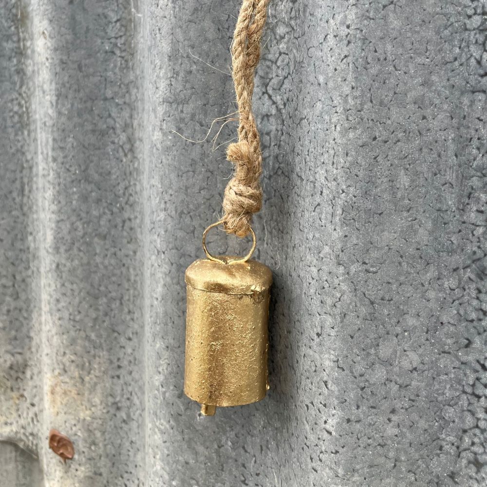 Mini Ages look brass bell hanging on a textured metal surface