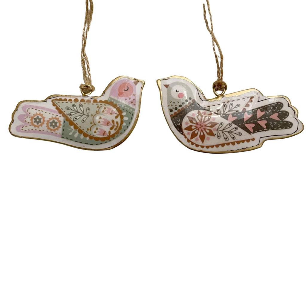 Two decorative metal nordic style bird ornaments with floral patterns on a white background