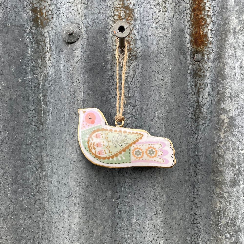 Decorative Metal Nordic bird ornament hanging on a textured metal surface