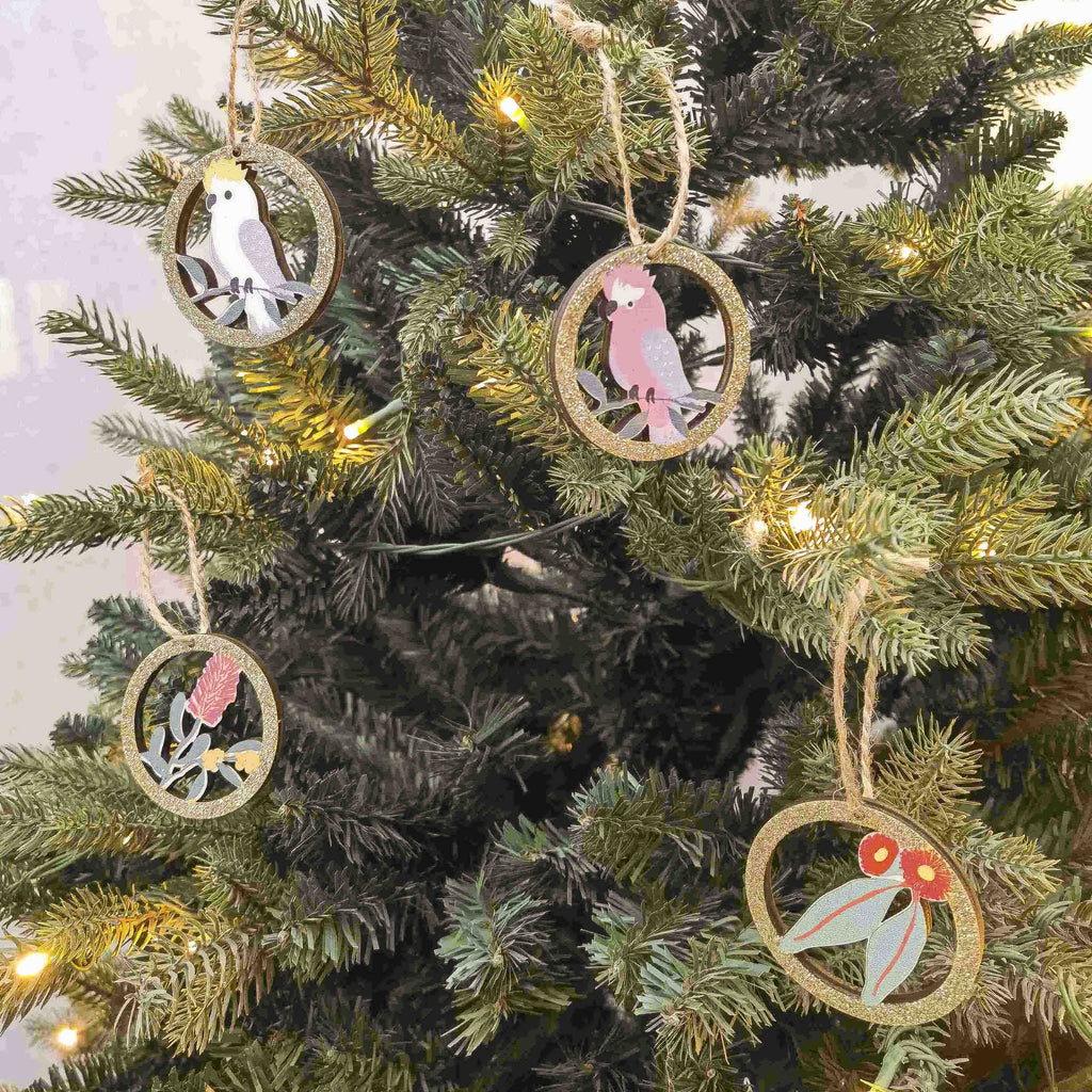 Decorative Christmas tree ornaments with Australian Bird and Flower illustrations hanging on a lit Christmas tree.