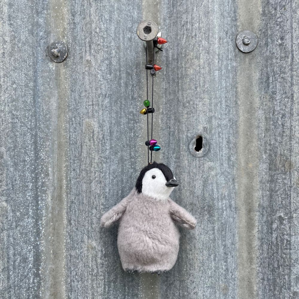 Decorative penguin hanging decoration with string lights on a corrugated background