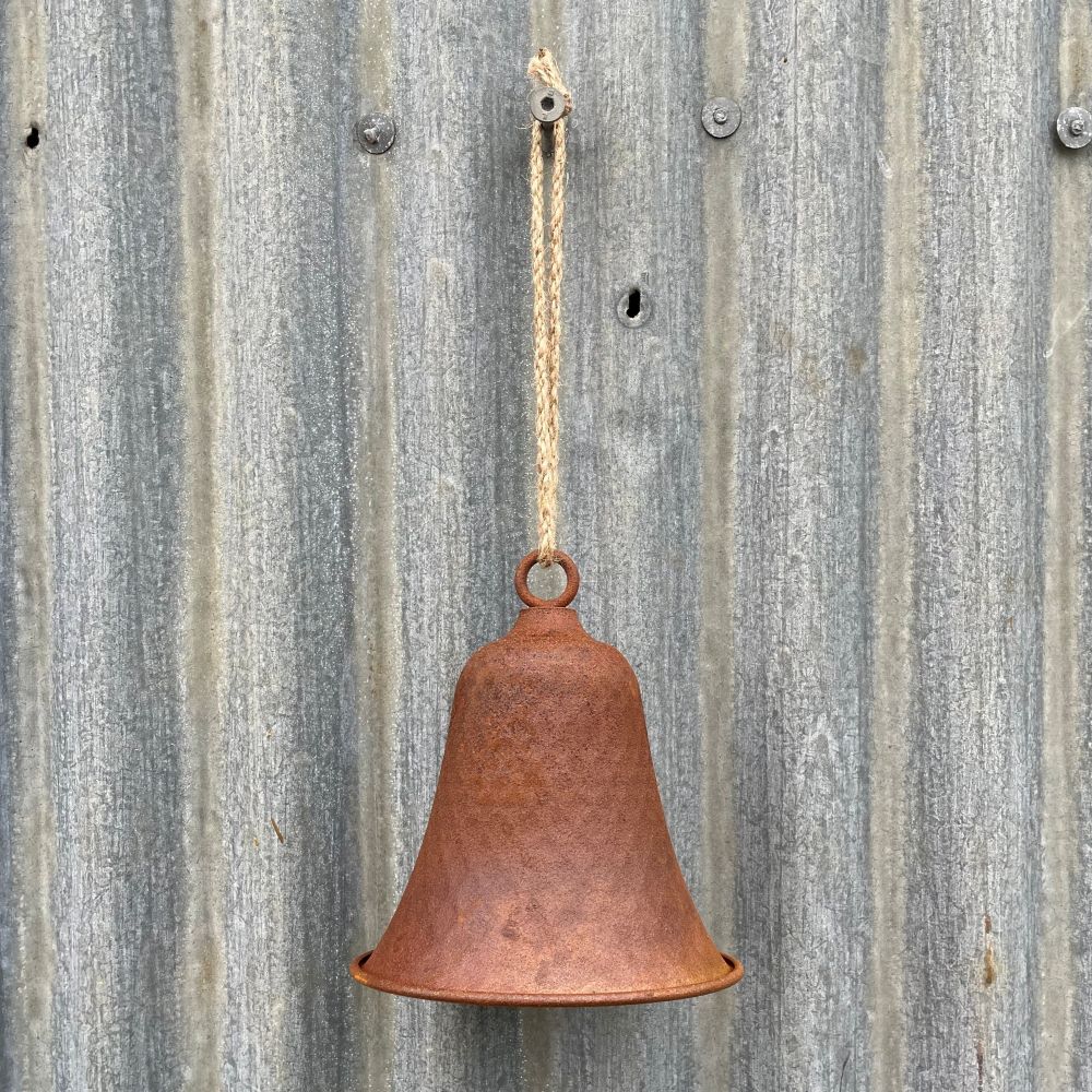 Rusty dimple bell hanging on a corrugated metal wall