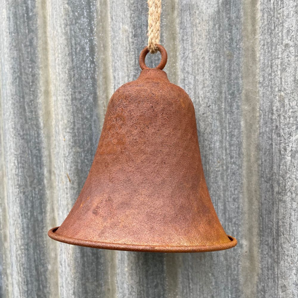 Rusty dimple bell hanging on a corrugated metal wall