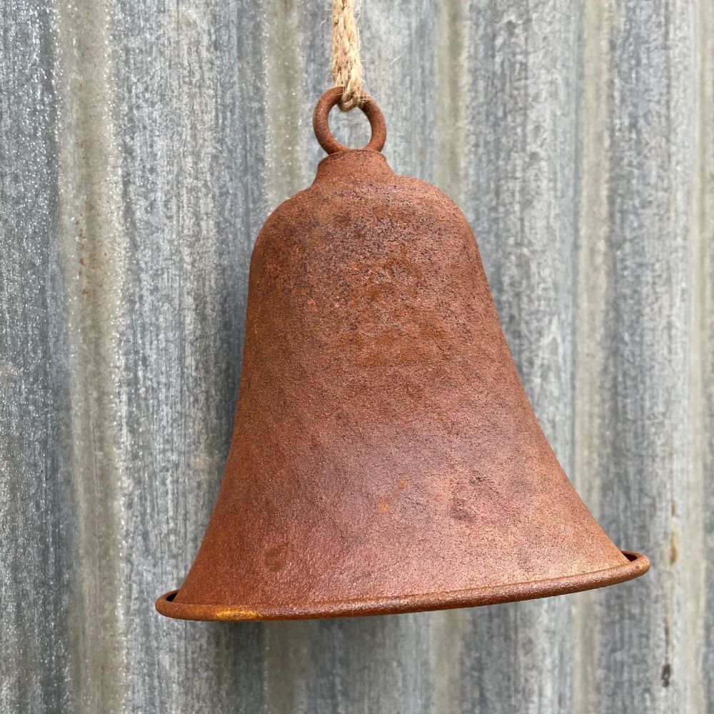 Rusty dimple bell hanging on a corrugated metal wall