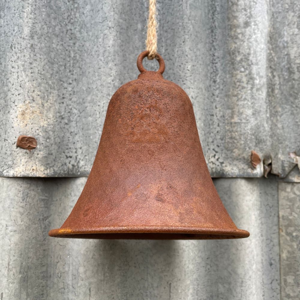 Rusty dimple bell hanging on a corrugated metal wall