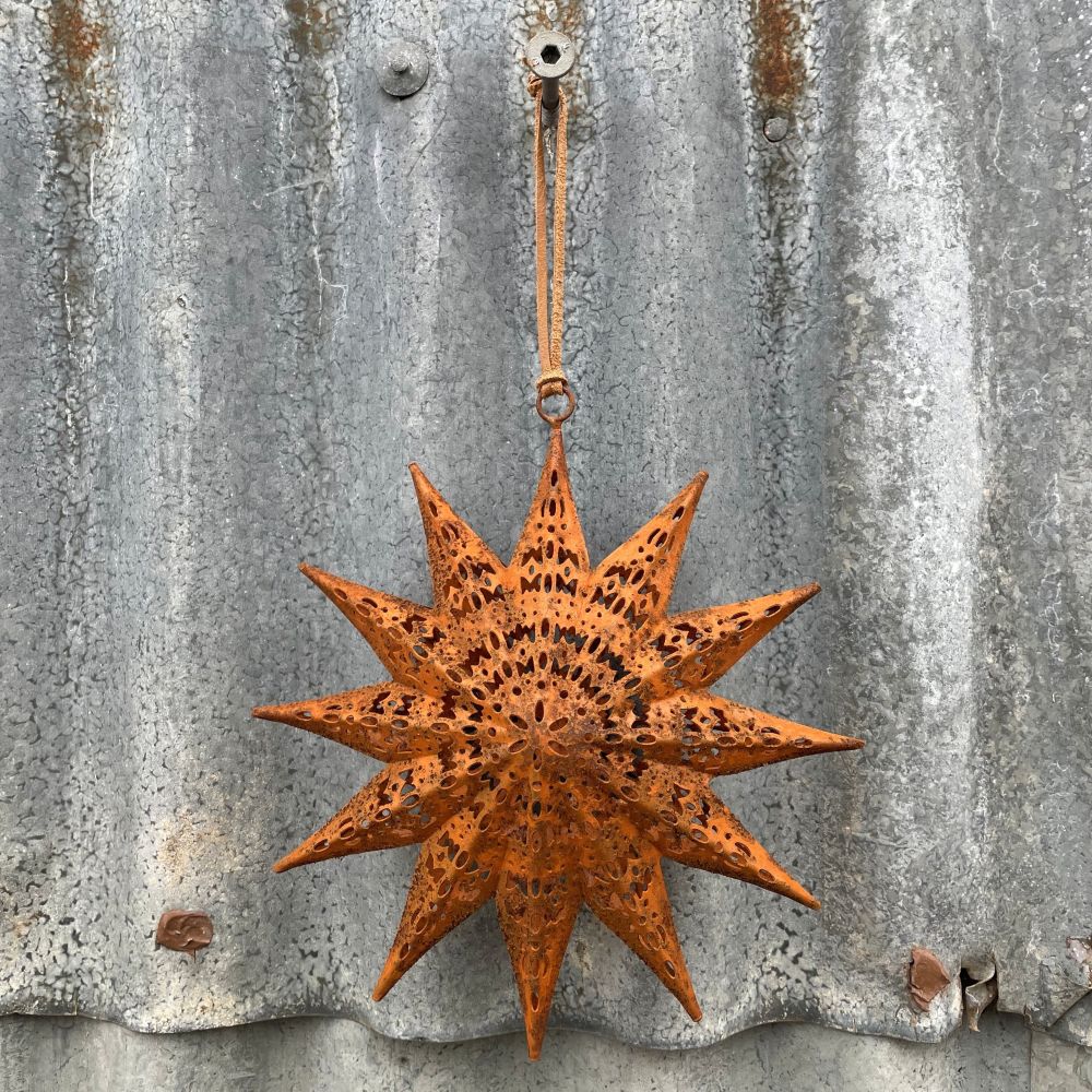 Rusty star-shaped ornament with etched patterns hanging on a corrugated metal surface