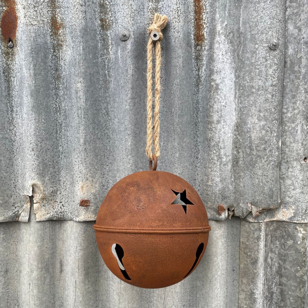 Rusty metal bell with cut-out stars hanging on a corrugated metal surface.