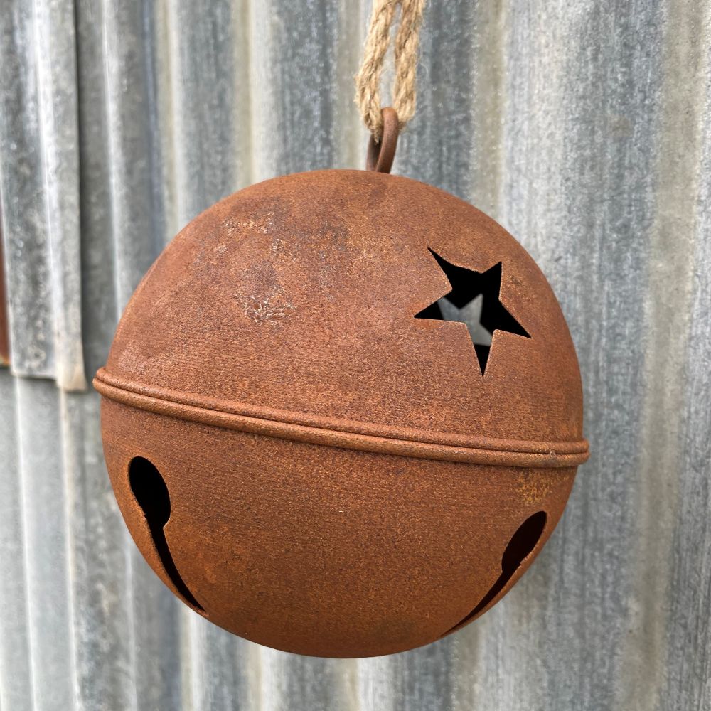 Rusty metal bell with cut-out stars hanging on a corrugated metal surface - detailed view