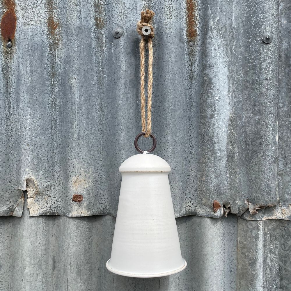 Large white/natural bell hanging on corrugated iron wall