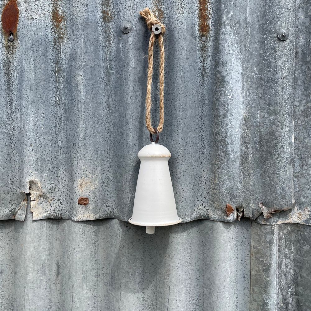 Small white/natural bell hanging on corrugated iron wall