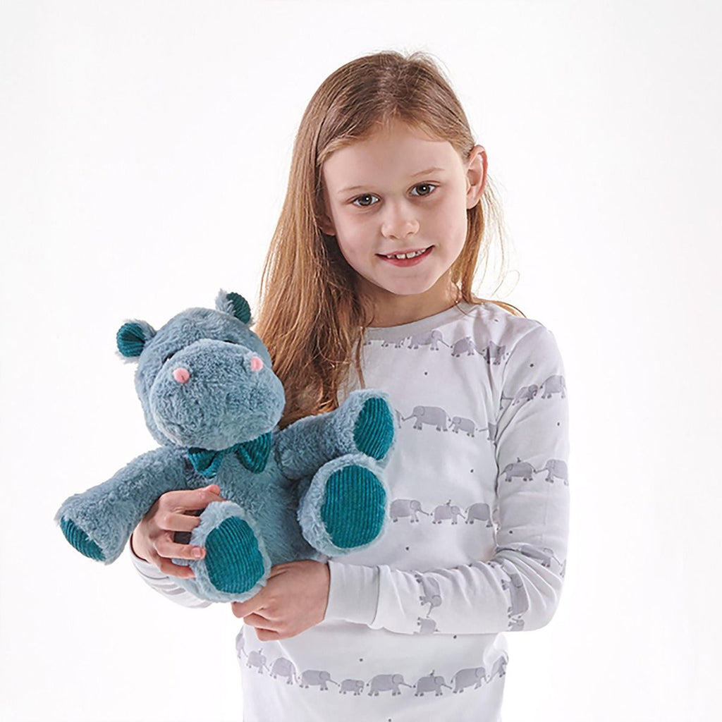 Young girl holding a plush snuggable hottie hippopotamus toy against a white background