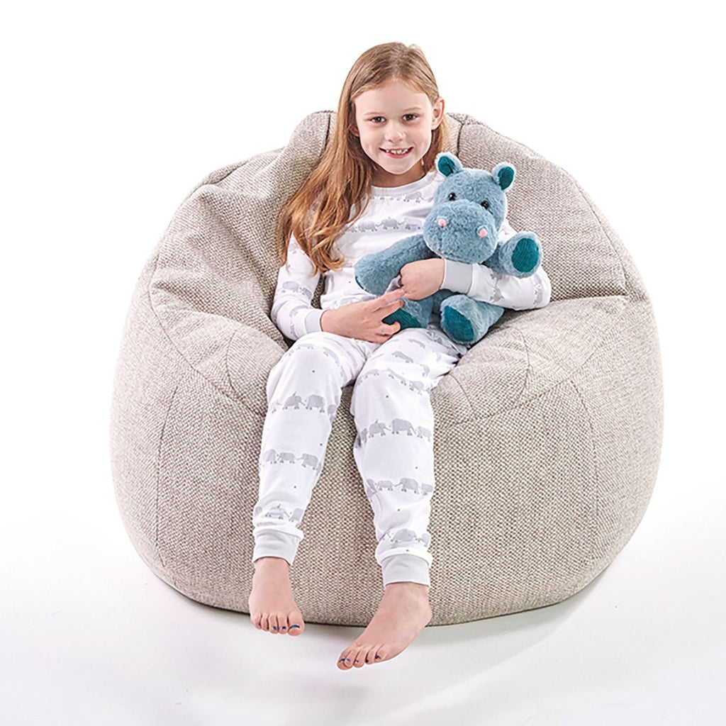 Child sitting on a bean bag chair holding a plush snuggable hottie toy, wearing matching pajamas.
