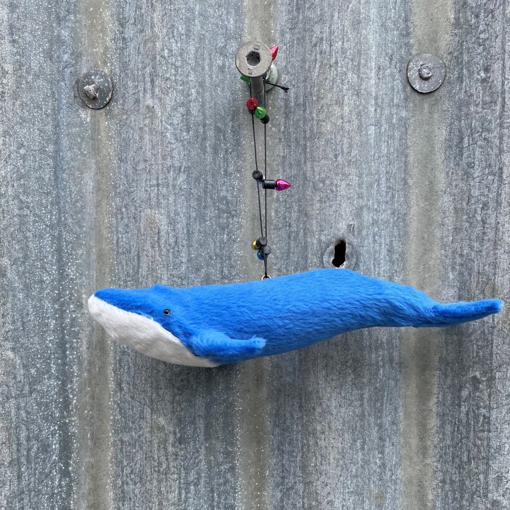 Blue whale decoration with string of lights on a corrugated metal wall background