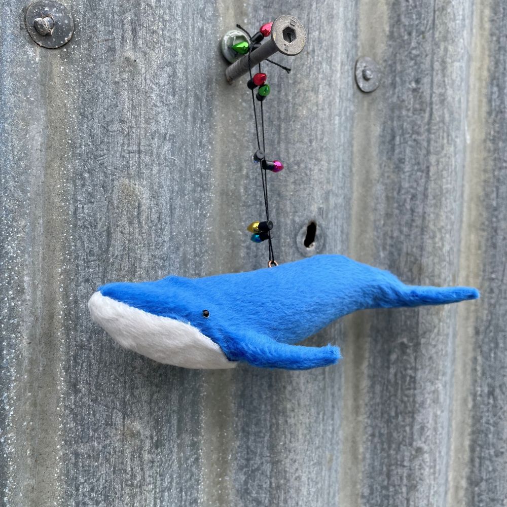 Blue whale decoration with string of lights on a corrugated metal wall background