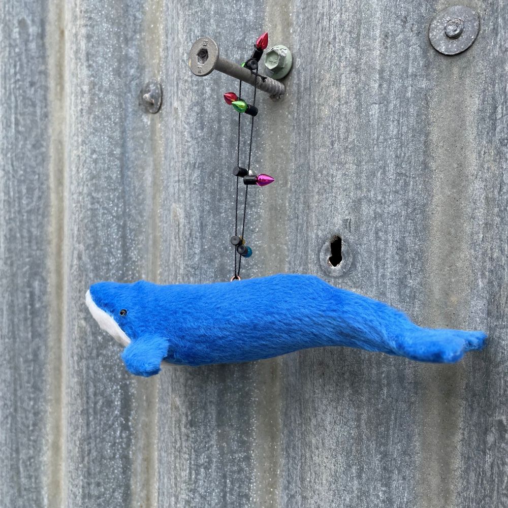 Blue whale decoration with string of lights on a corrugated metal wall background