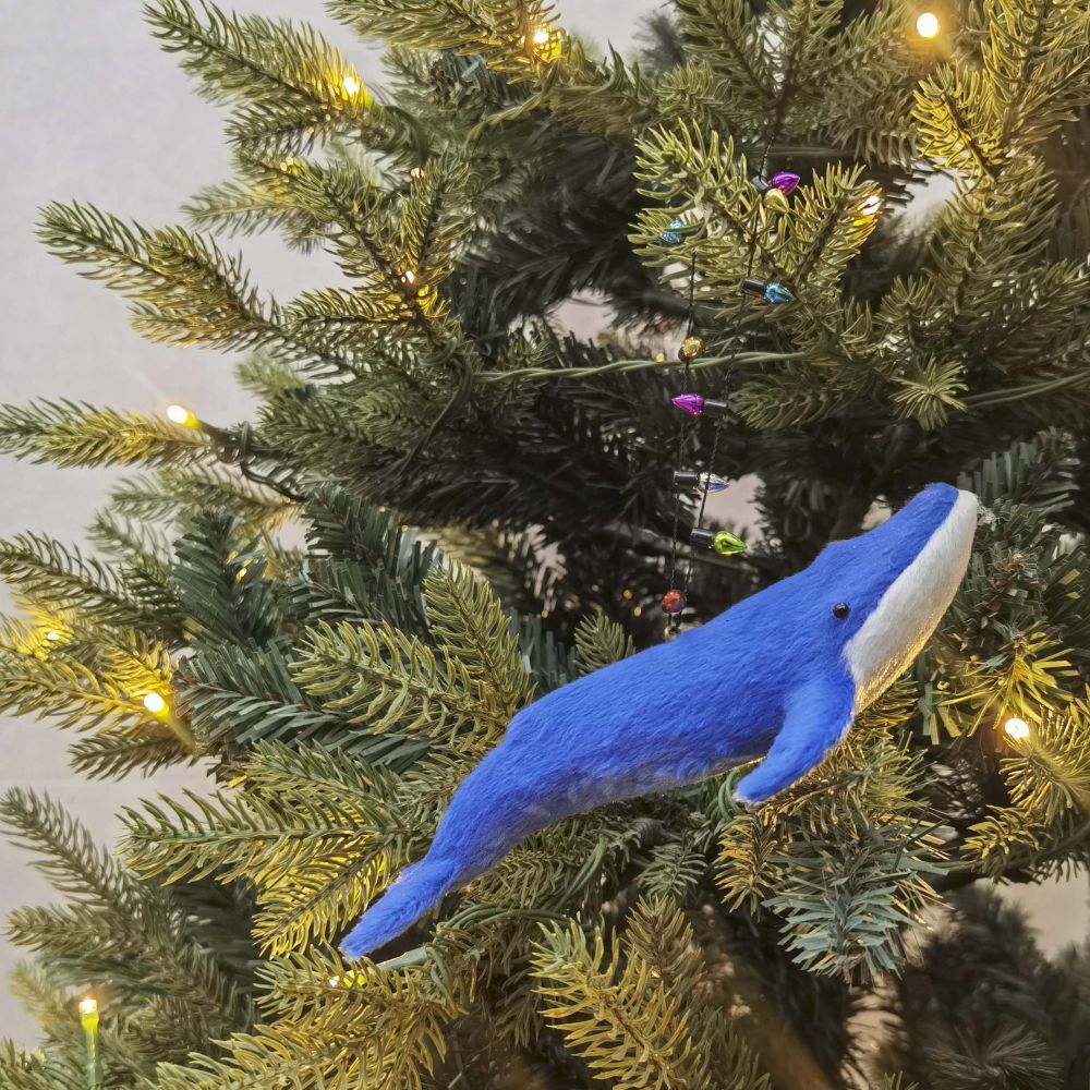 Blue whale decoration with string of lights hanging on a Christmas tree