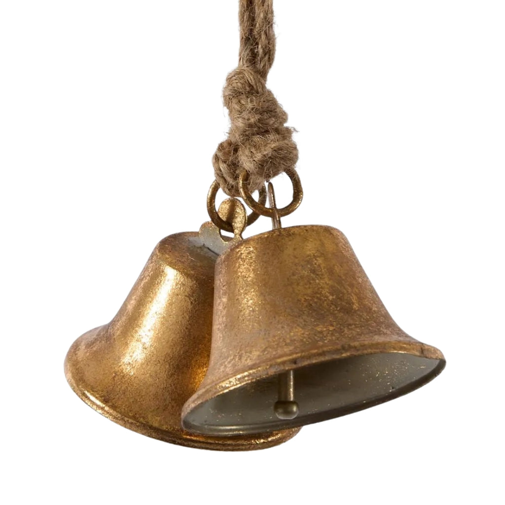 Pair of rustic antique style gold bells hanging on a rope against a white background