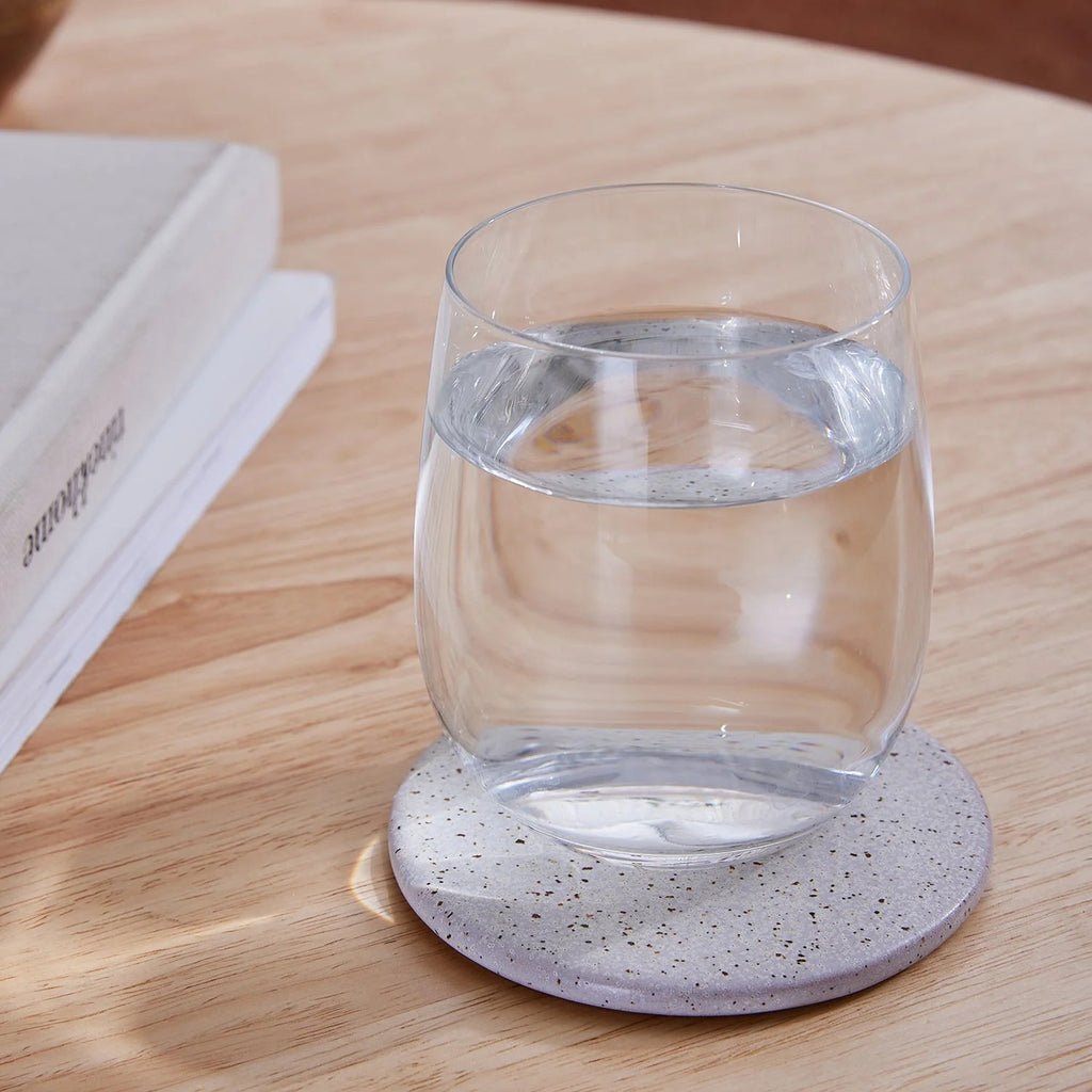 Twig and Feather - Ceramic coaster with a speckle finish in neutral stone colour  - styled with a glass -  by Madras Link