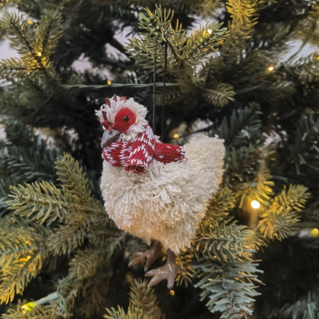 Decorative chicken ornament on a Christmas tree with lights.