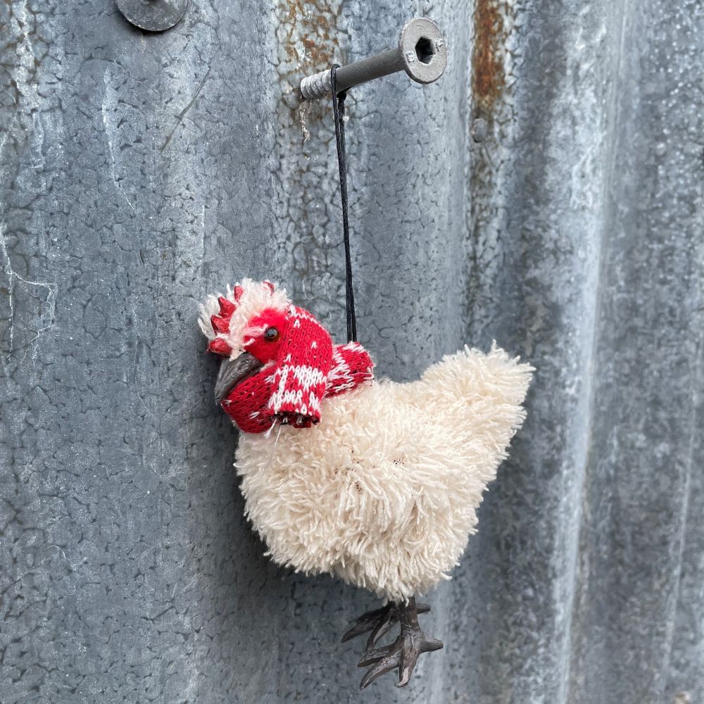 Chicken ornament with red comb and red and white scarf hanging to a metal surface
