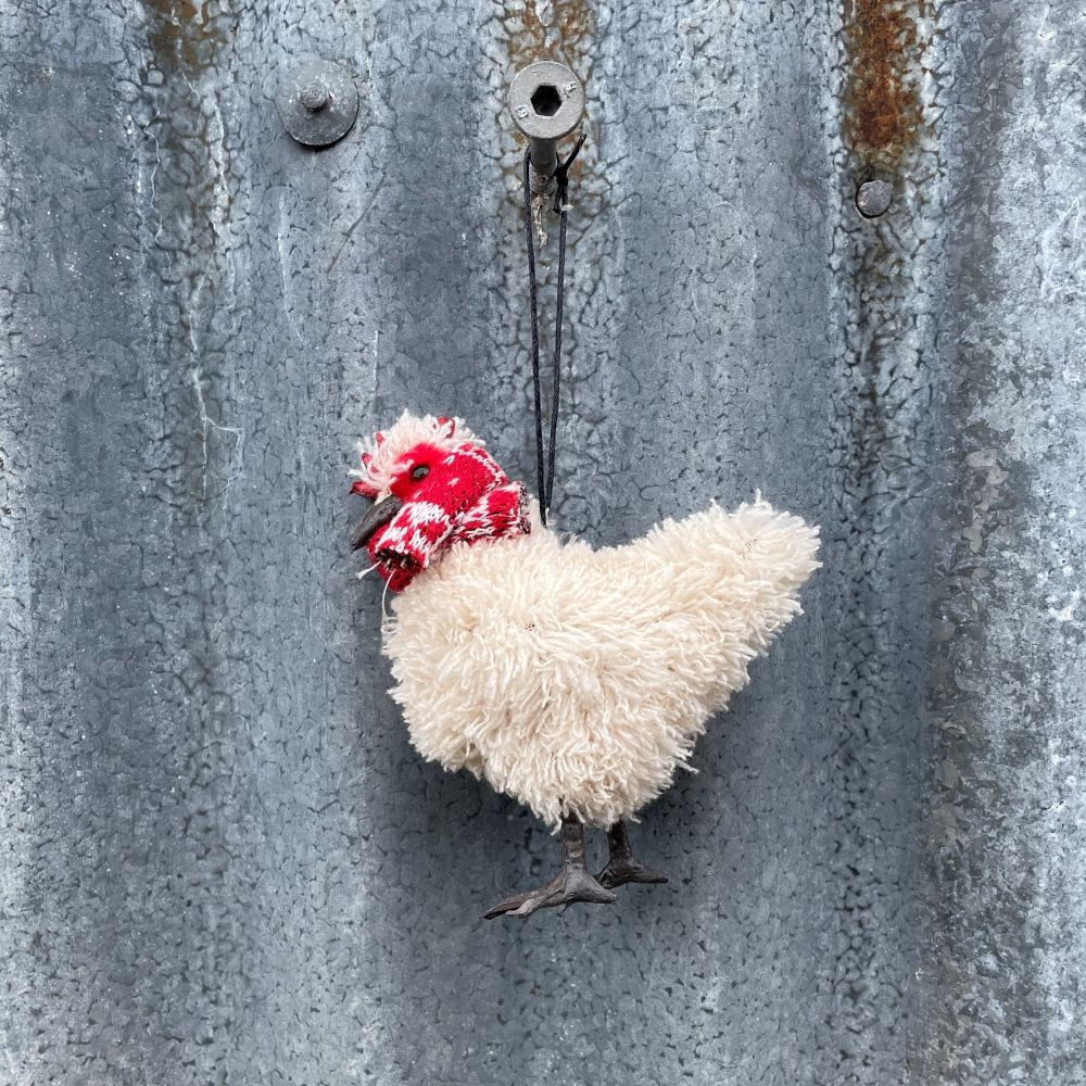 Decorative chicken ornament with a red scarf on a textured metal surface