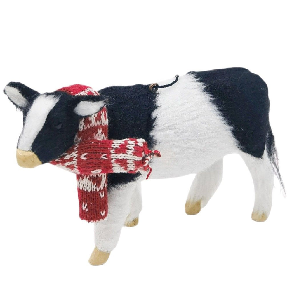 Hanging Christmas cow decoration wearing a red and white patterned scarf on a white background