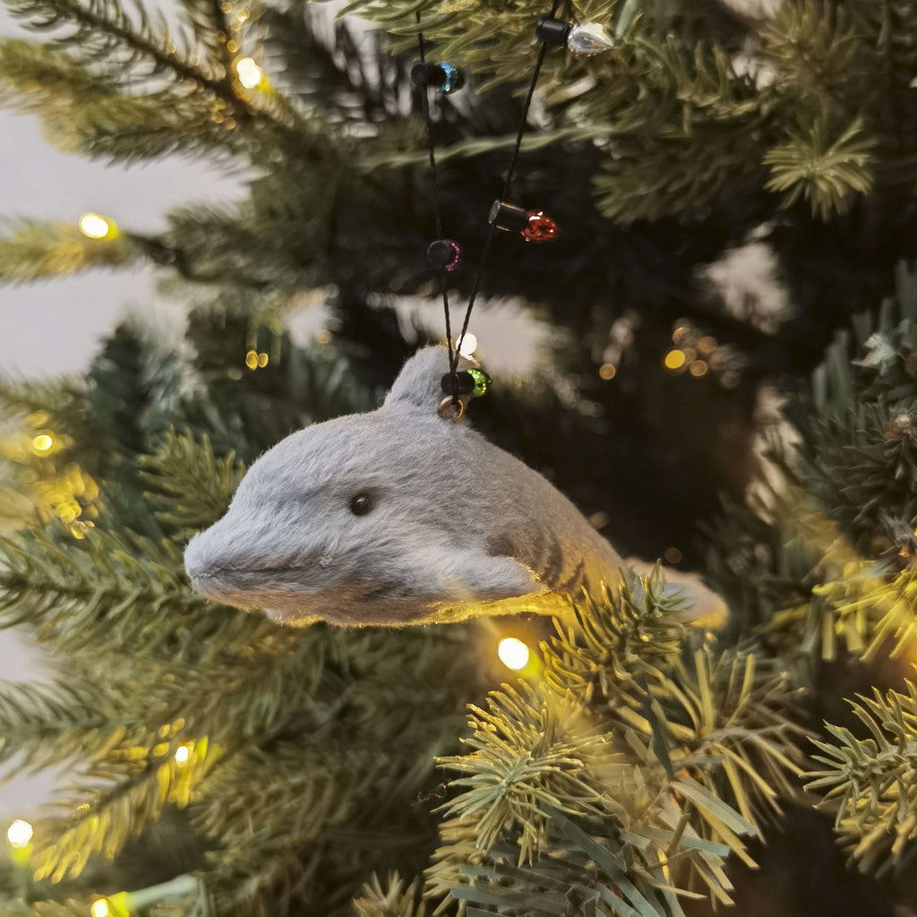Gray dolphin ornament on a decorated Christmas tree with lights.