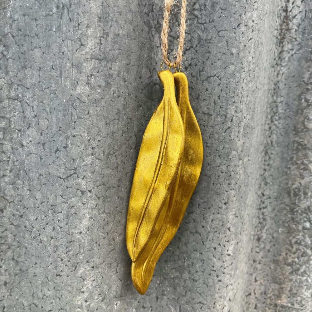 Gold leaf pendant hanging against a textured gray background