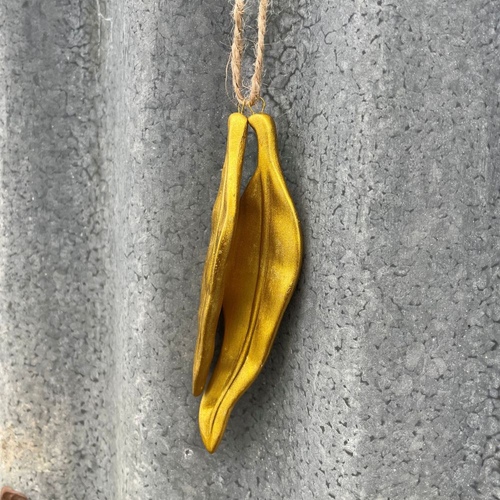 Gold leaf-shaped ornament hanging on a textured gray surface