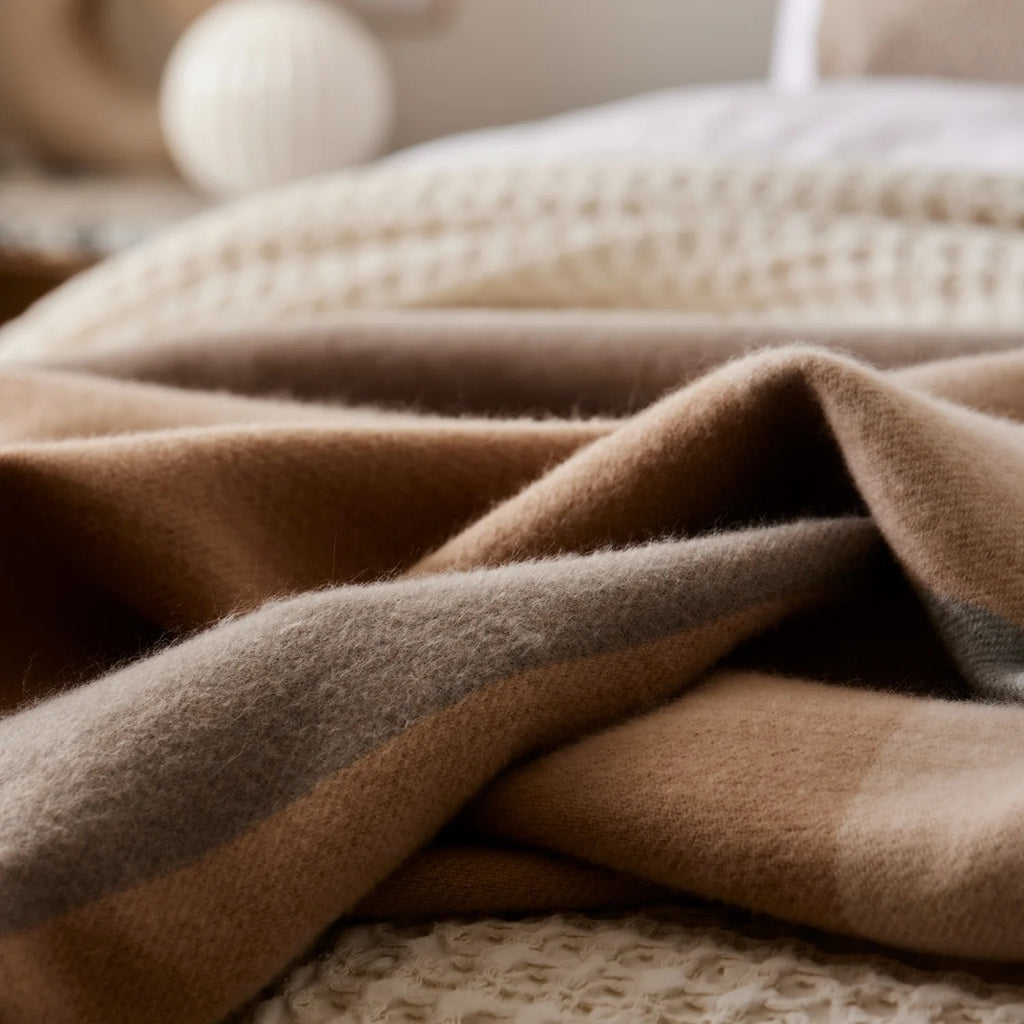 Close-up of a textured Harley charcoal Beige/neutral check throw rug on a soft focus background