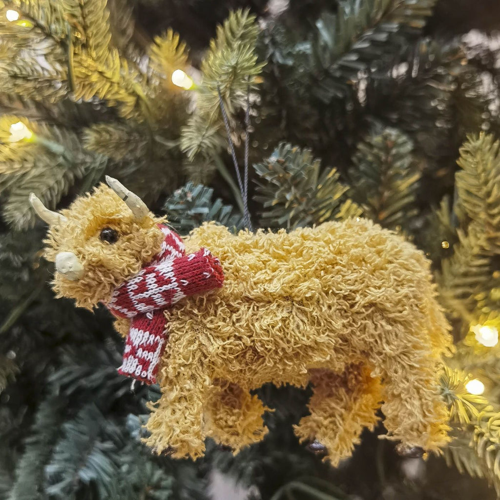 Highland cow christmas decoration wearing a red and white striped scarf on a Christmas tree.