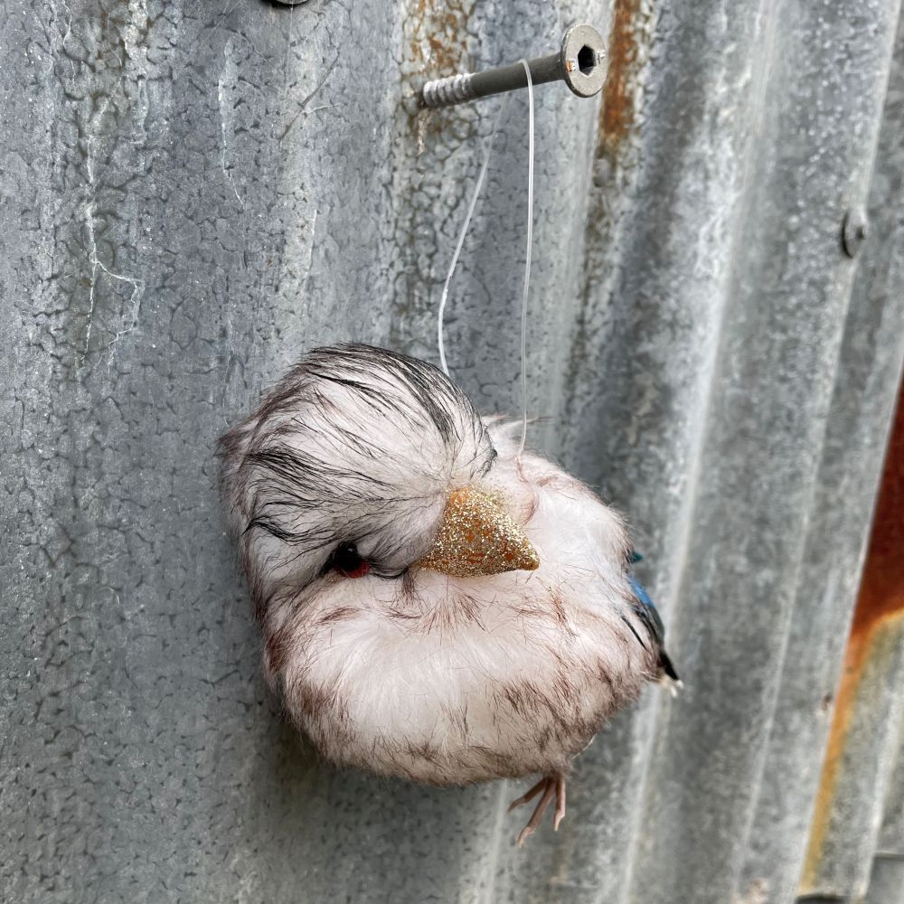 Decorative Australian Kookaburra ornament made of feathers on a textured metal surface - other side view