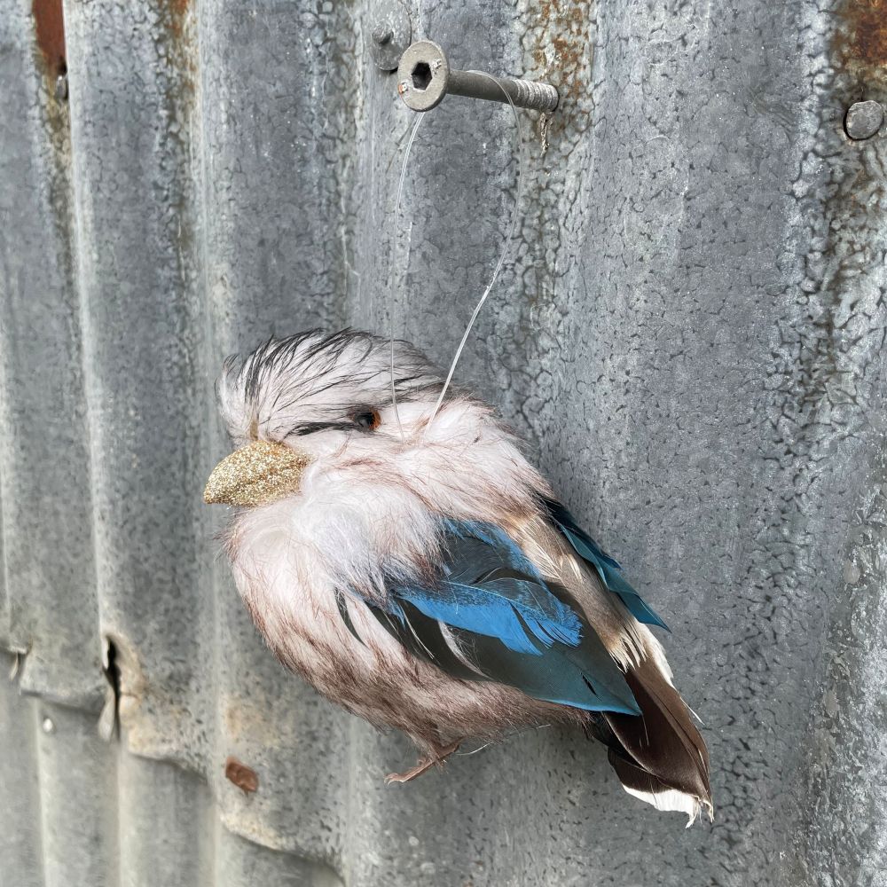 Decorative Australian Kookaburra ornament made of feathers on a textured metal surface - side view