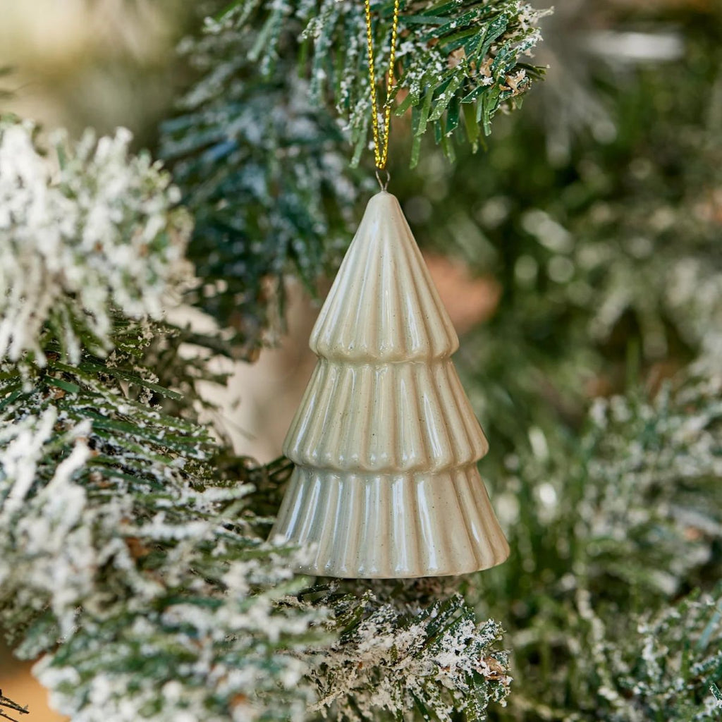 Ceramic Christmas tree-shaped ornament in sage green hanging on a green Christmas tree