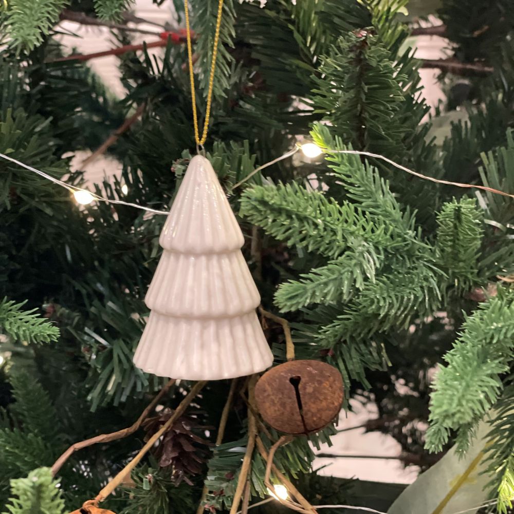 White ribbed Christmas tree ornament hanging on a decorated tree.