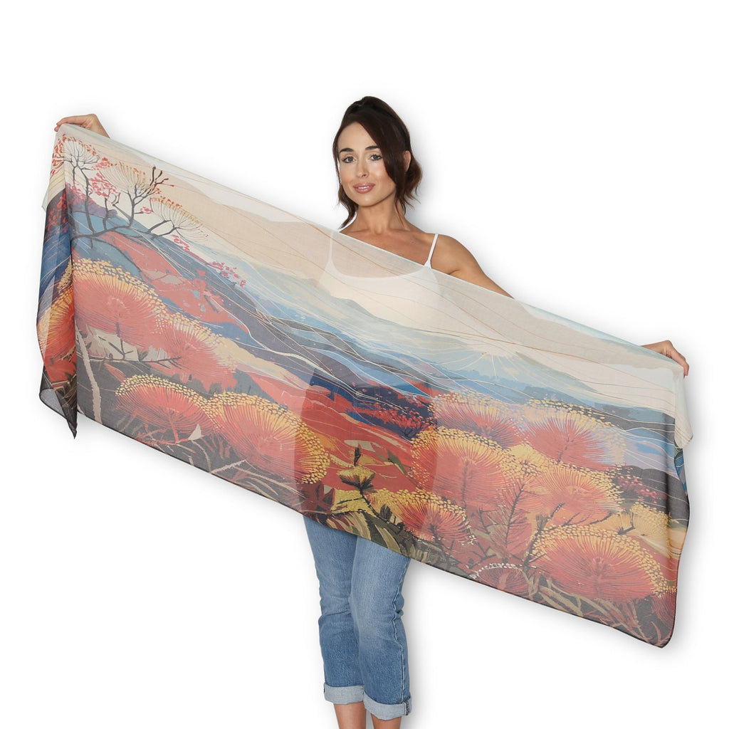 Woman holding The Artist Label Blue Mountains Golden Hour scarf in deep oranges and browns with wattle blossoms and mountains