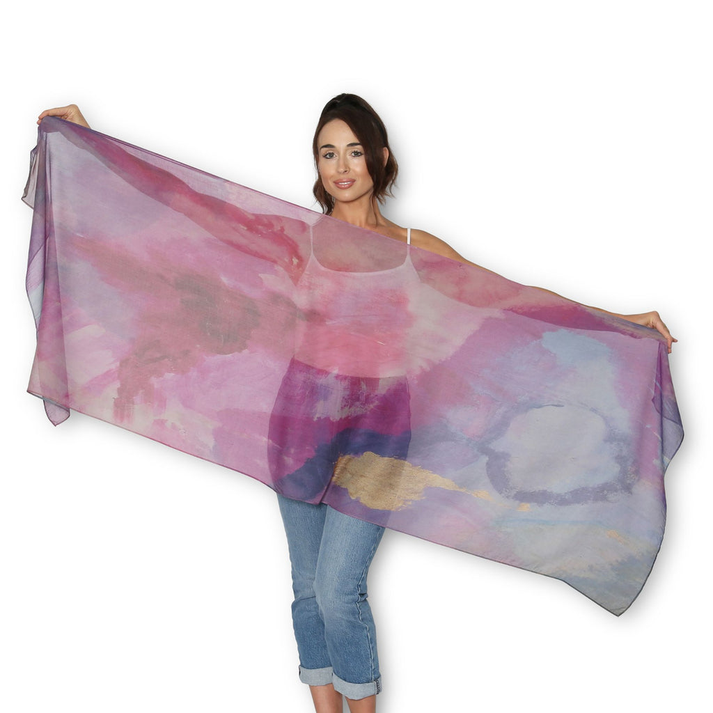 Woman holding up The Artist Label Feminism scarf in purples, violets, lilacs and hinds of gold. 